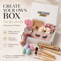 Surprise & Shine customizable gift box with makeup brushes, false lashes, scrunchies, butterfly necklace, makeup sponges, and a compact mirror.